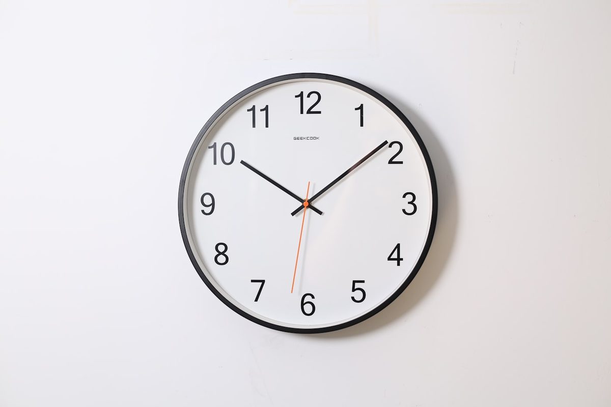 Black-rimmed round wall clock with orange second hand
